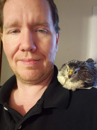 a young chicken sitting on a man's shoulder