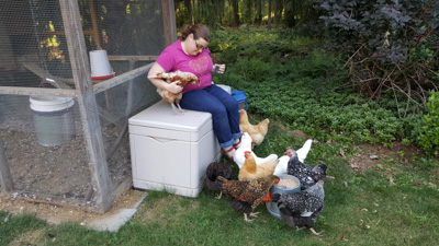a woman with a flock of chickens outside a chicken coop